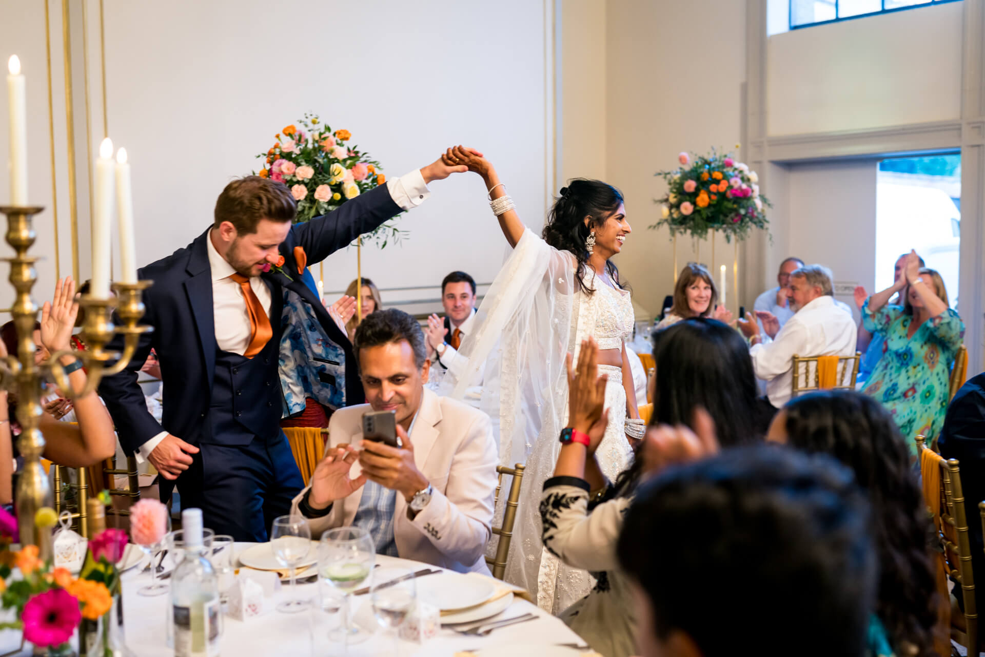 Joyful wedding couple dancing among guests at reception