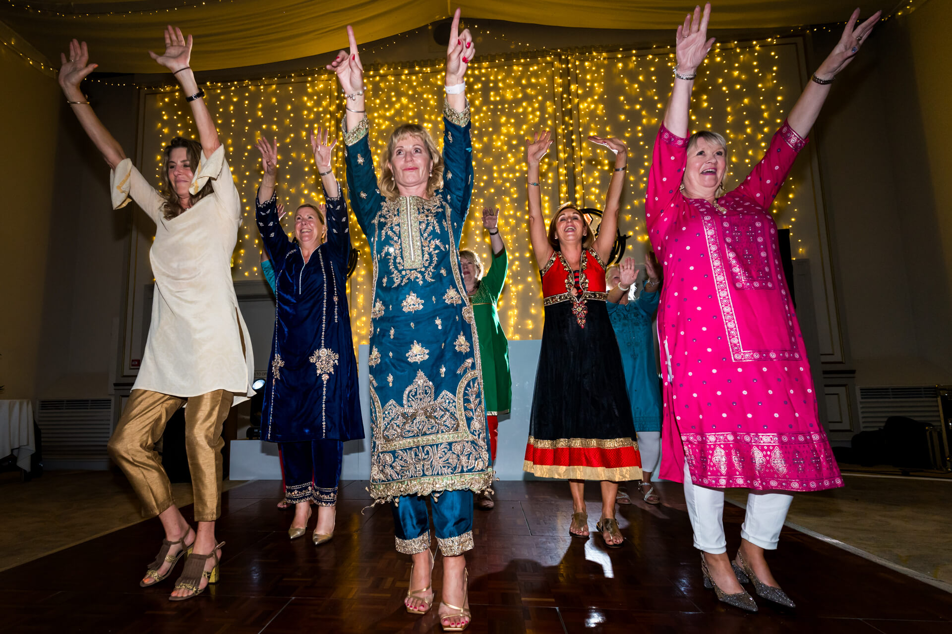 Wedding guests dancing in traditional Indian attire.