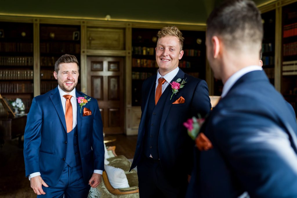 Groomsmen in suits sharing a moment in library.