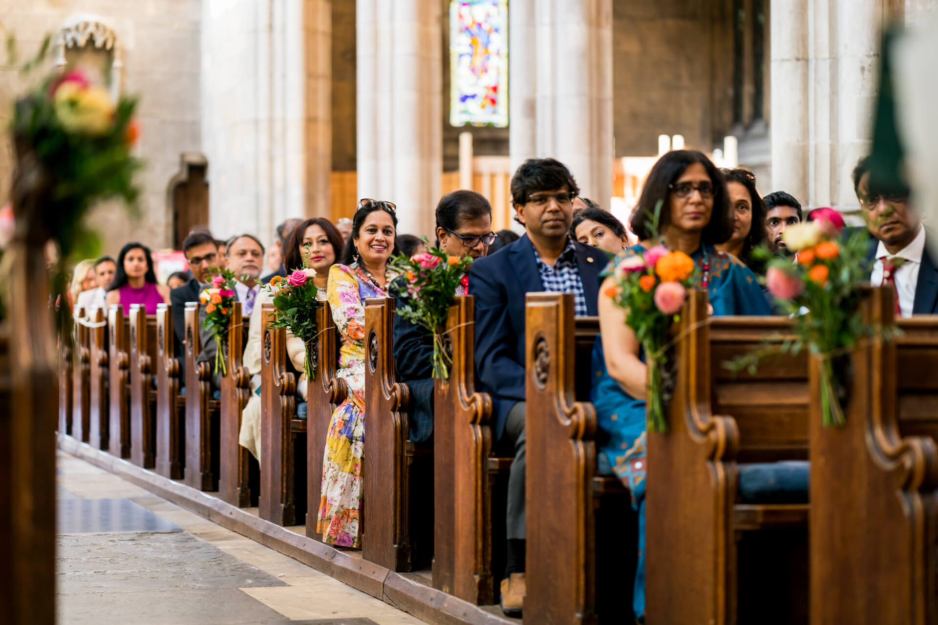 Wedding guests seated in church with floral decorations.