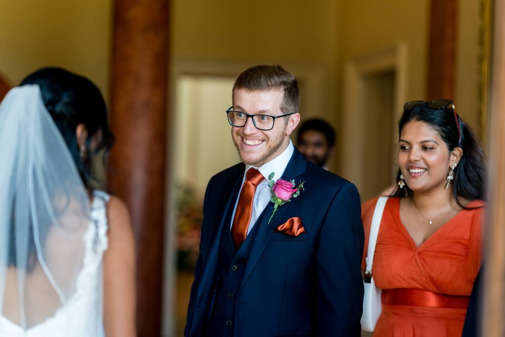 Groomsman smiling at bride, wedding guests, joyous occasion.