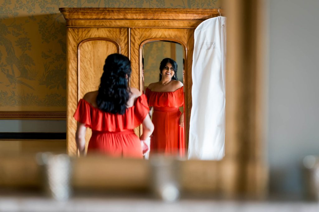 bridesmaid in red dress admiring reflection, elegant interior.