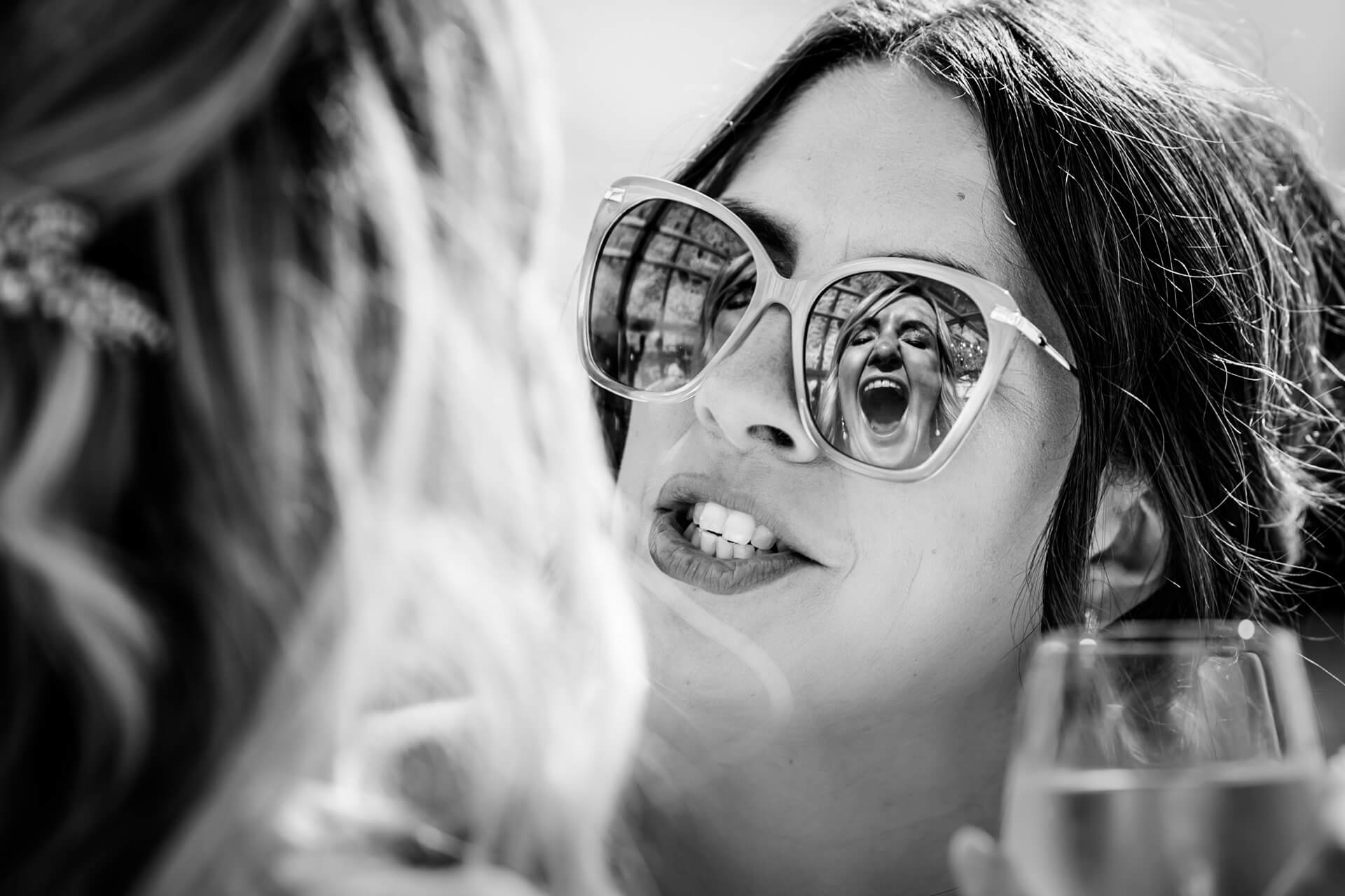 Bride laughing, reflection in sunglasses, black and white photo.
