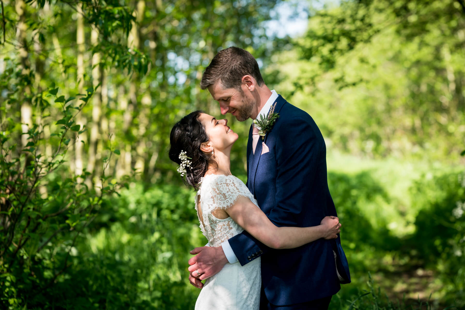Couple embracing in sunlit woodland setting