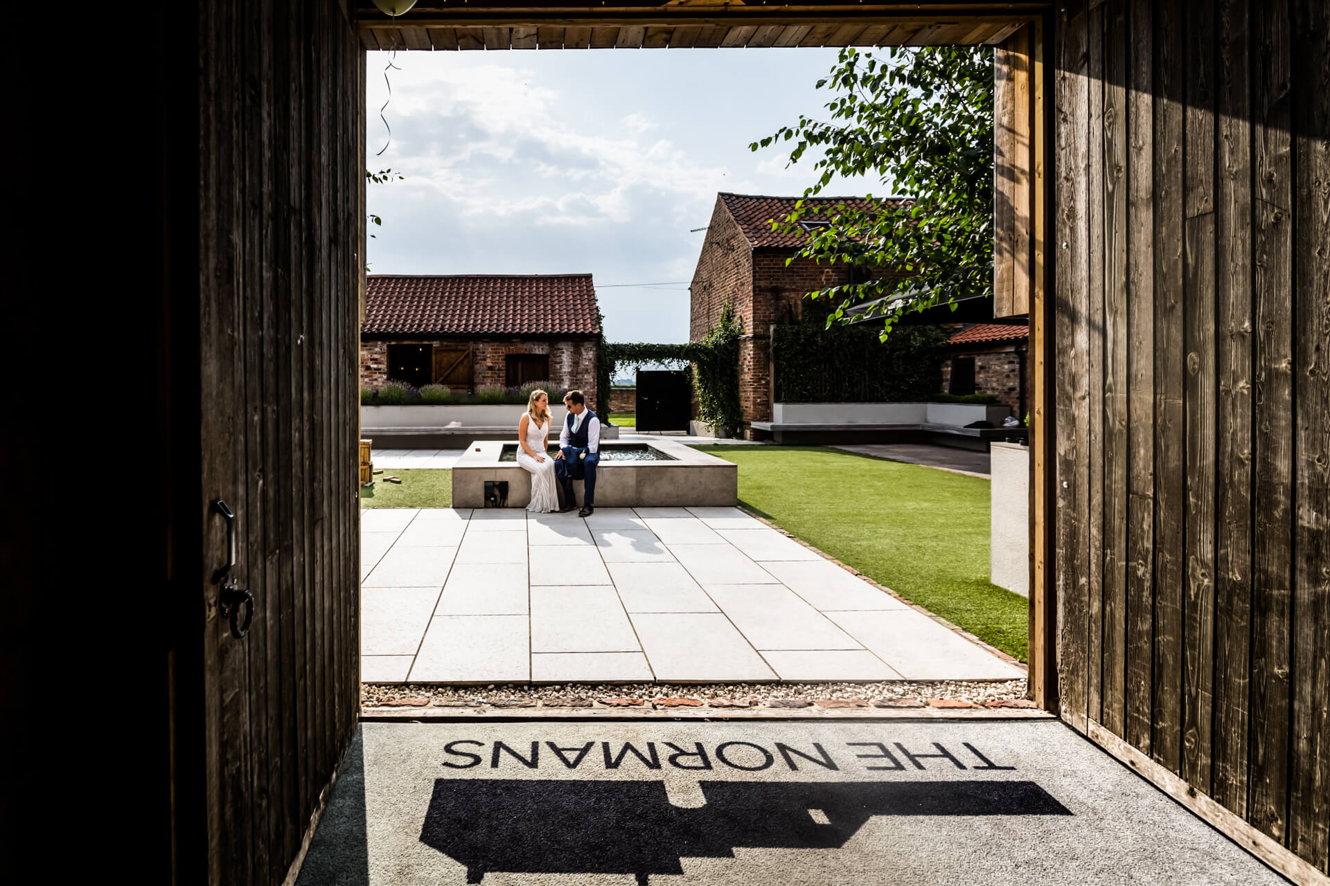 Couple sitting in courtyard at The Normans, viewed through open door.