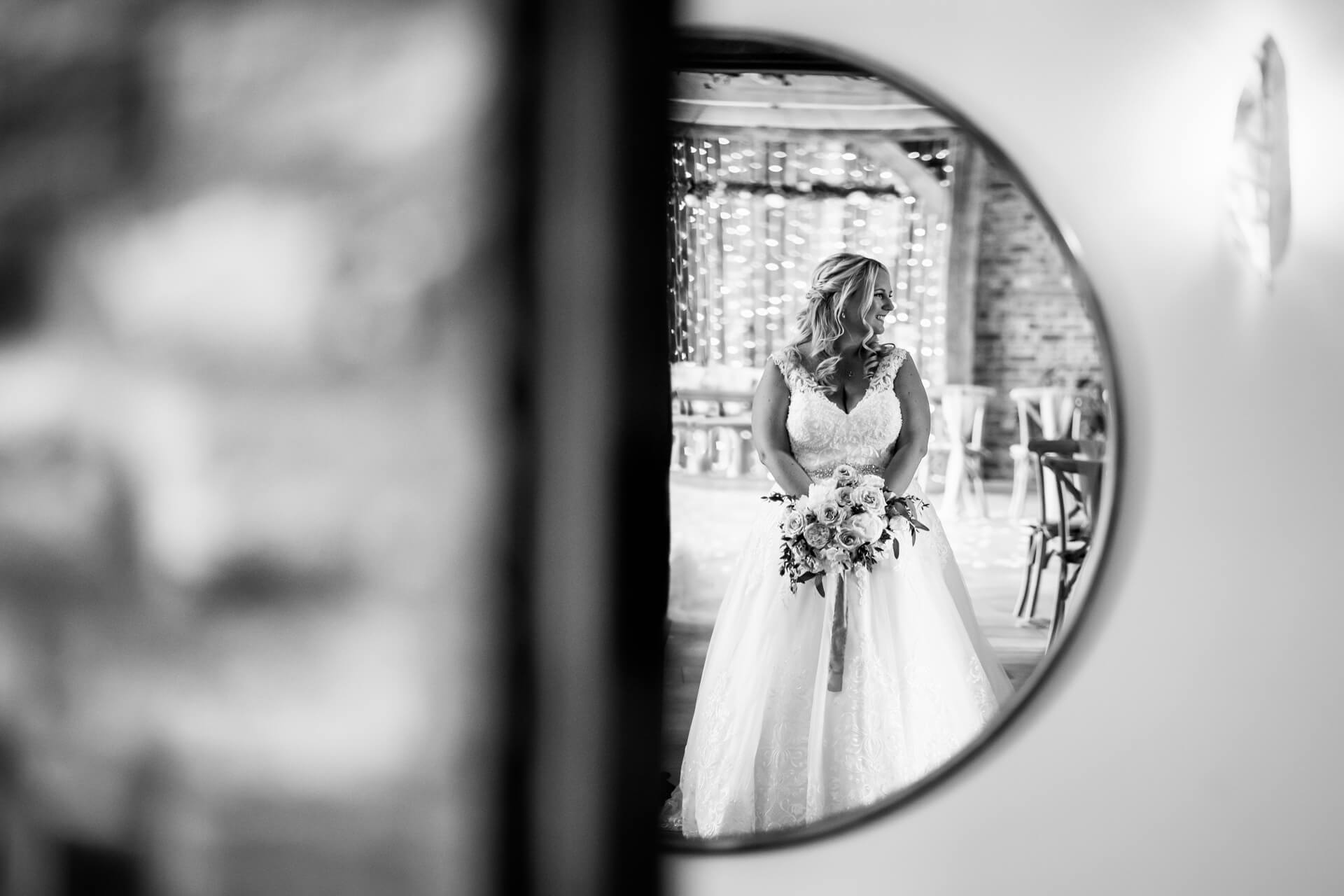 Bride reflected in mirror holding bouquet at wedding venue.