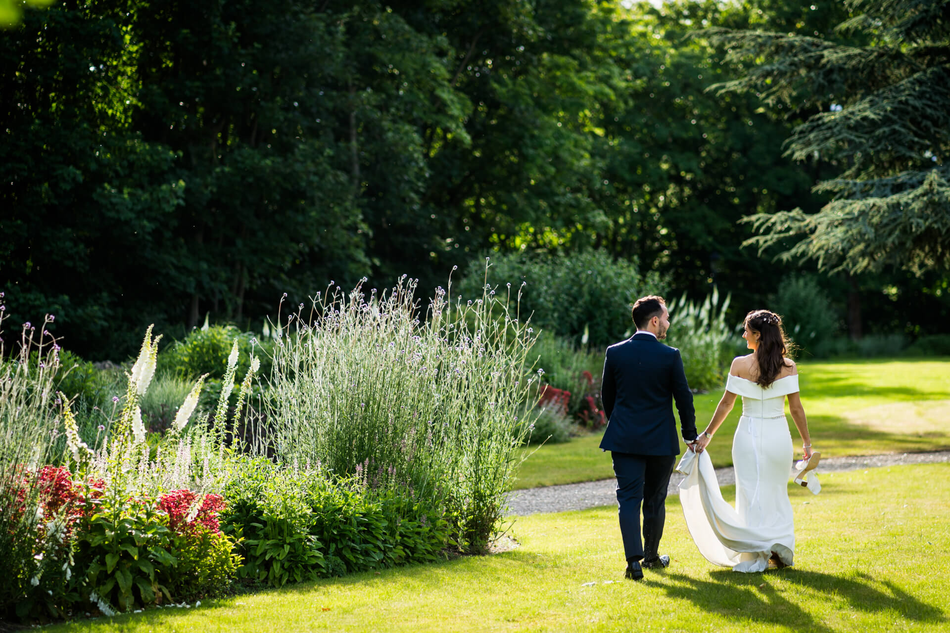 Bride and groom walking in lush garden at Bowcliffe Hall