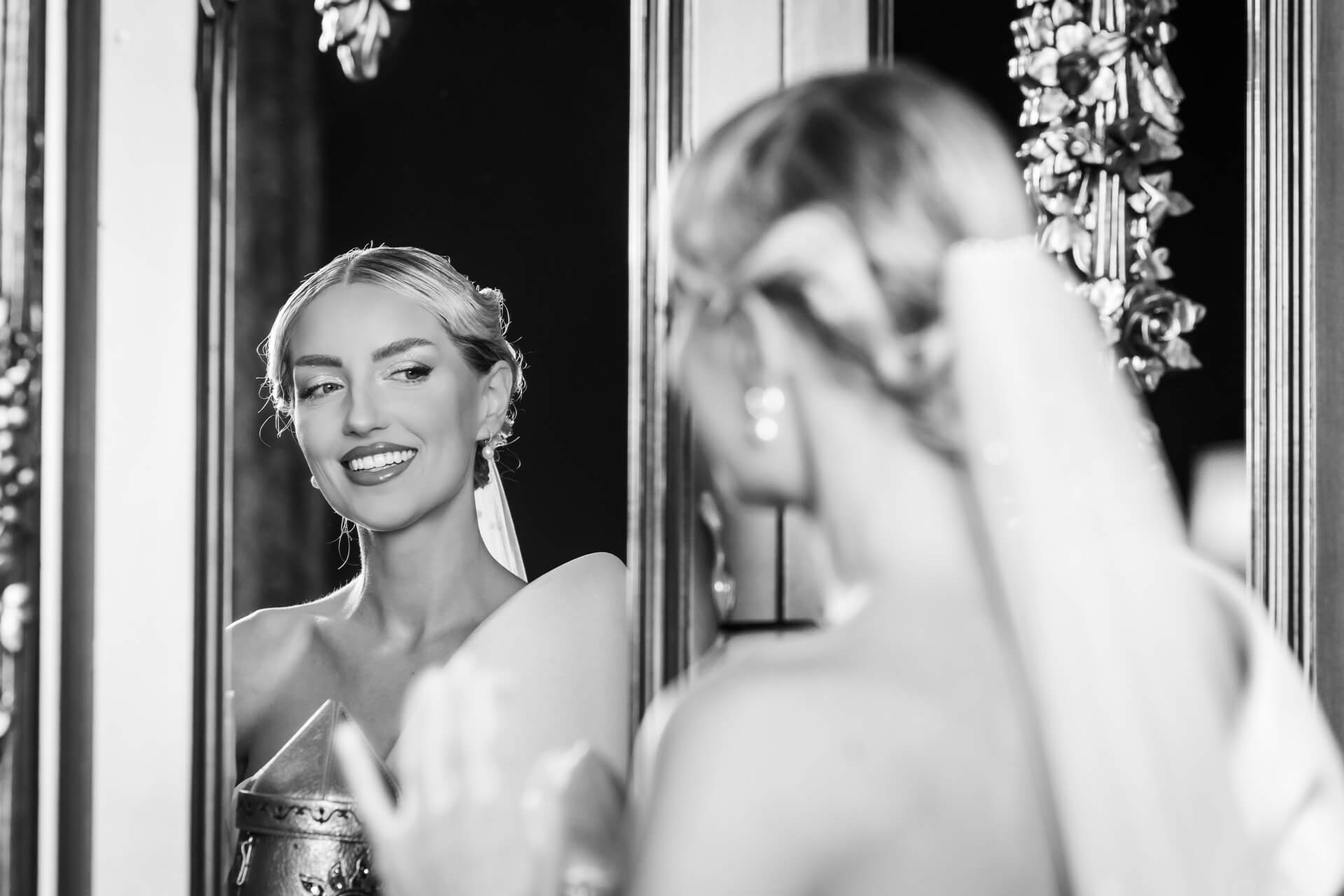 Bride smiling at reflection in ornate mirror