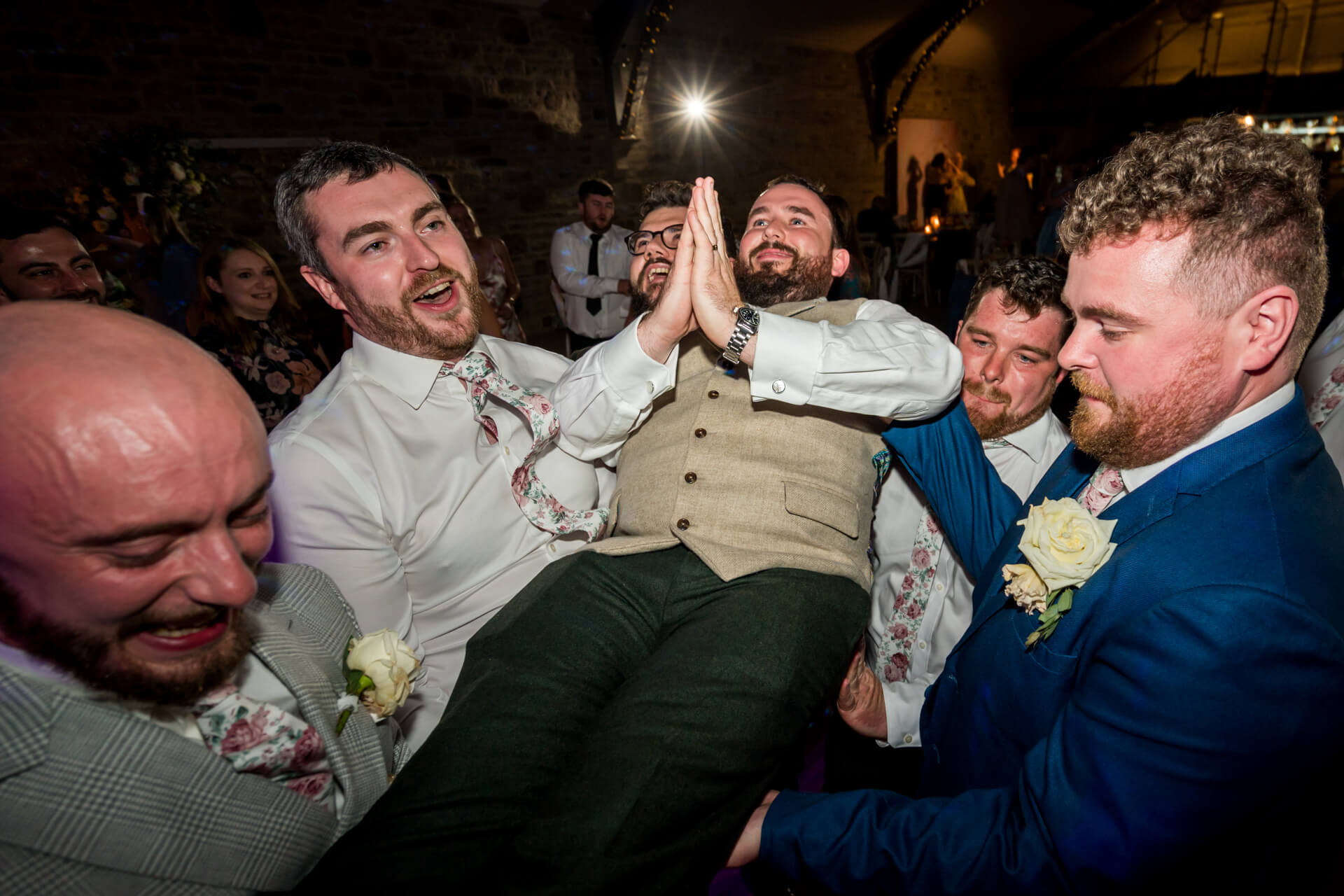 Groomsmen lifting groom in jubilant wedding celebration indoors at the Yorkshire Wedding Barn