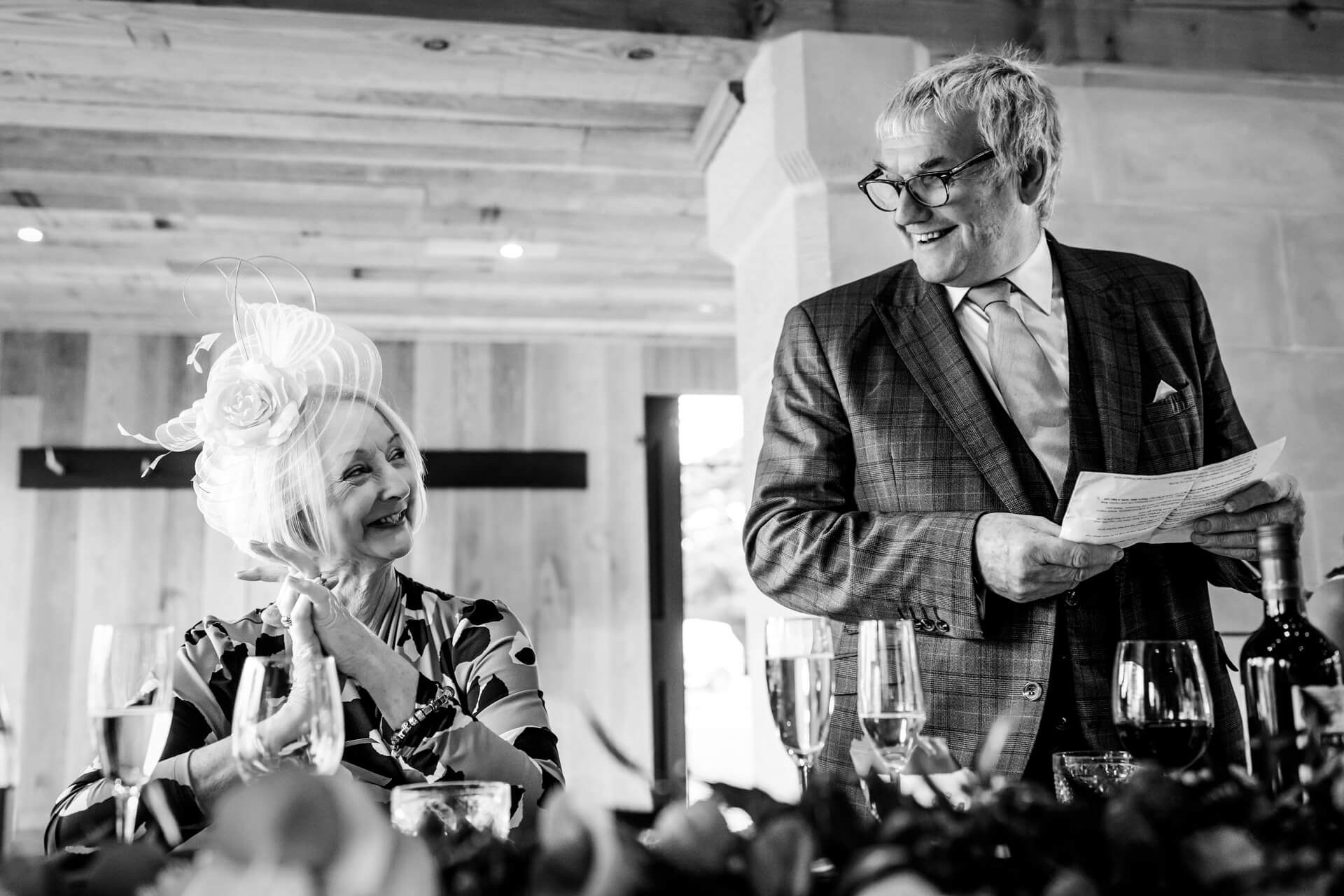 Elderly couple smiling at wedding toast in black and white