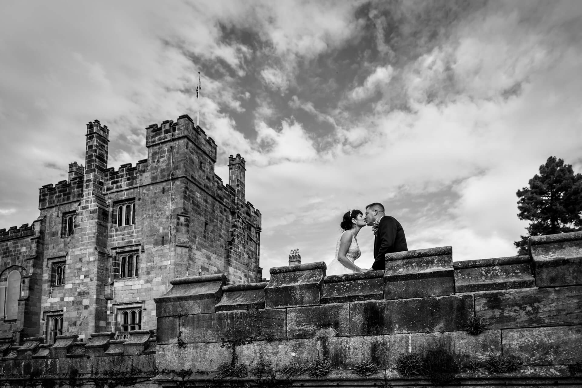 Couple kissing by historic Ripley Castle in black and white