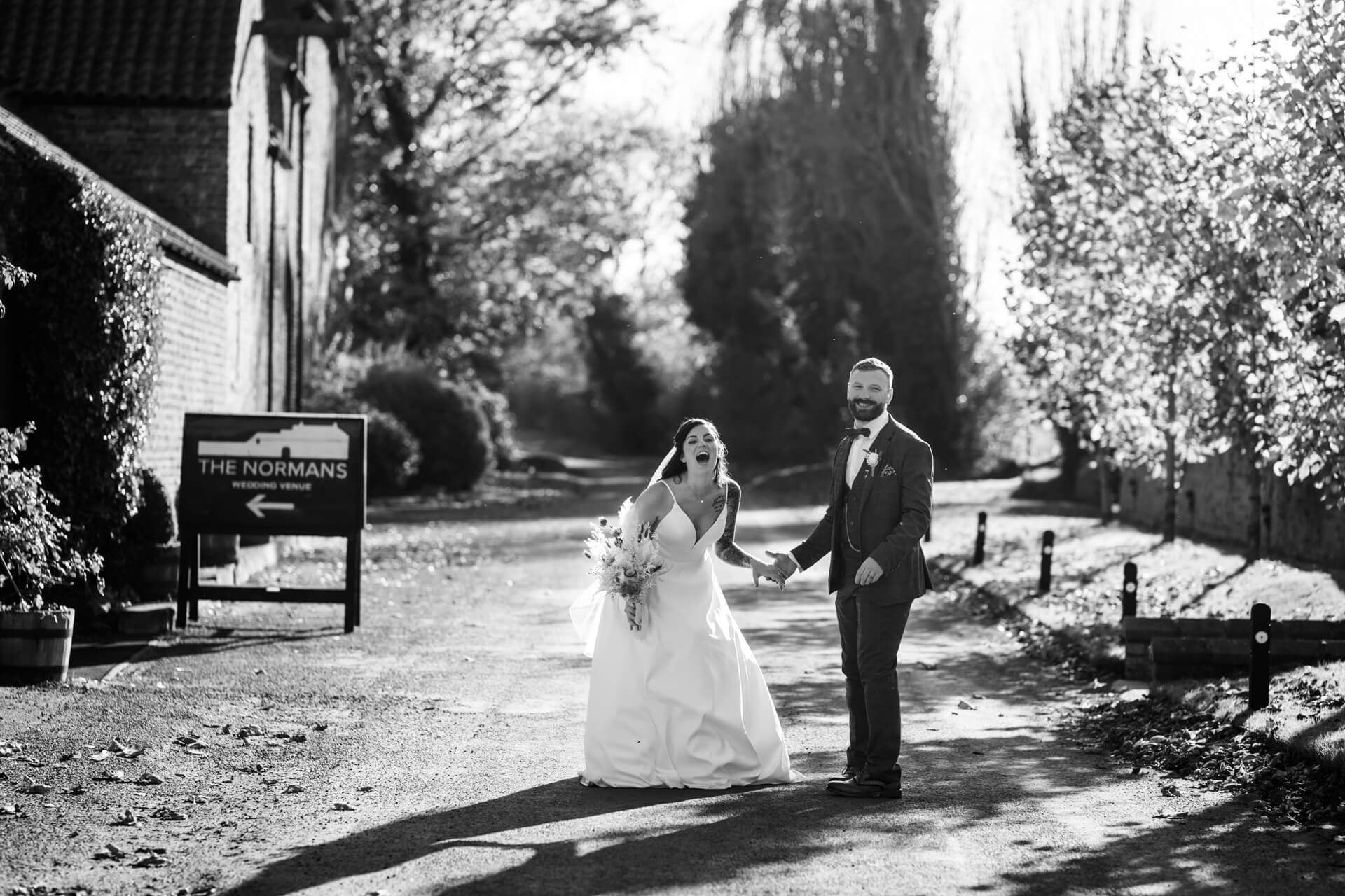 Joyful bride and groom walking at 'The Normans' venue.