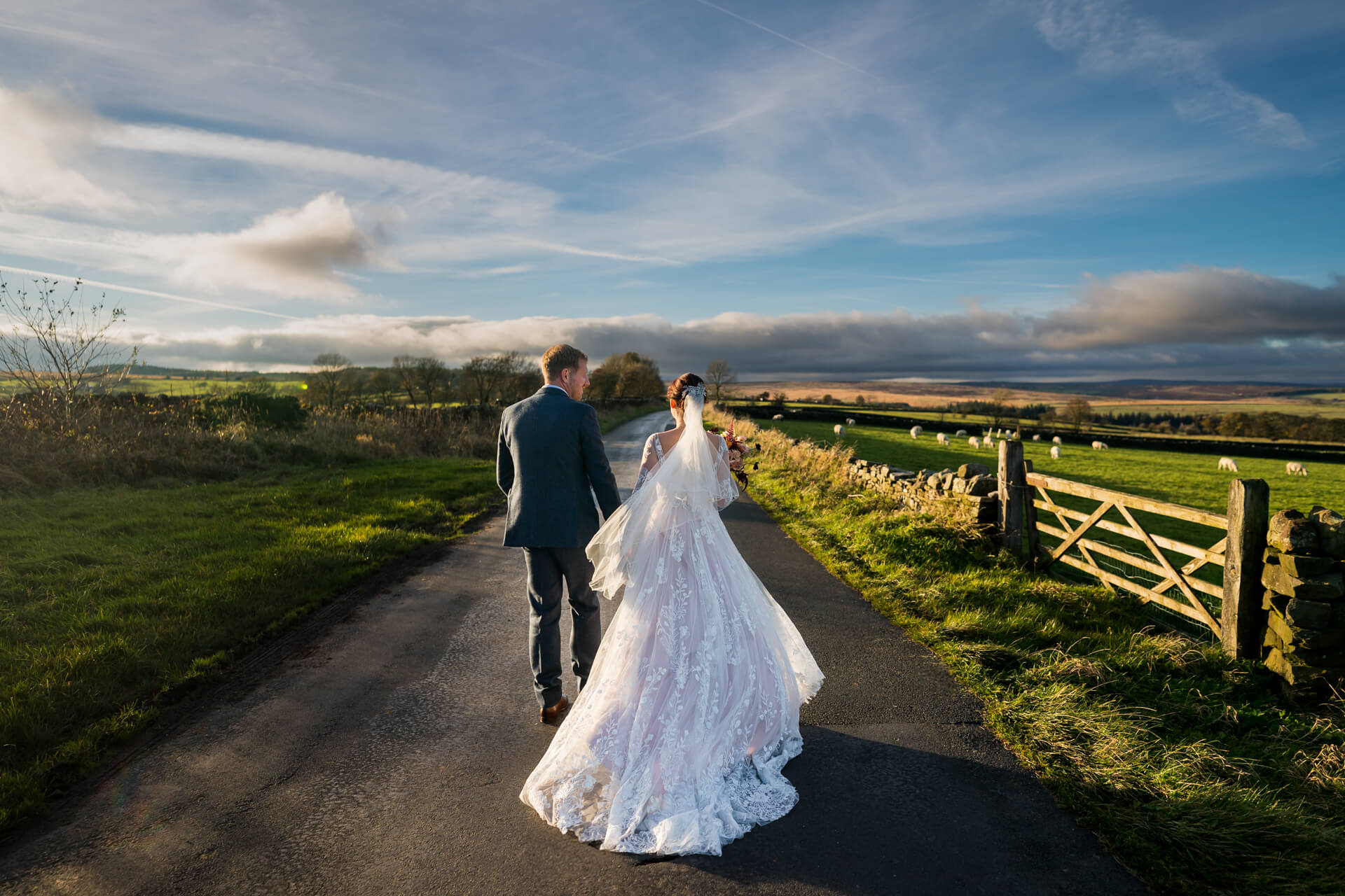 Bride and groom walking on rural Yorkshire road, scenic backdrop