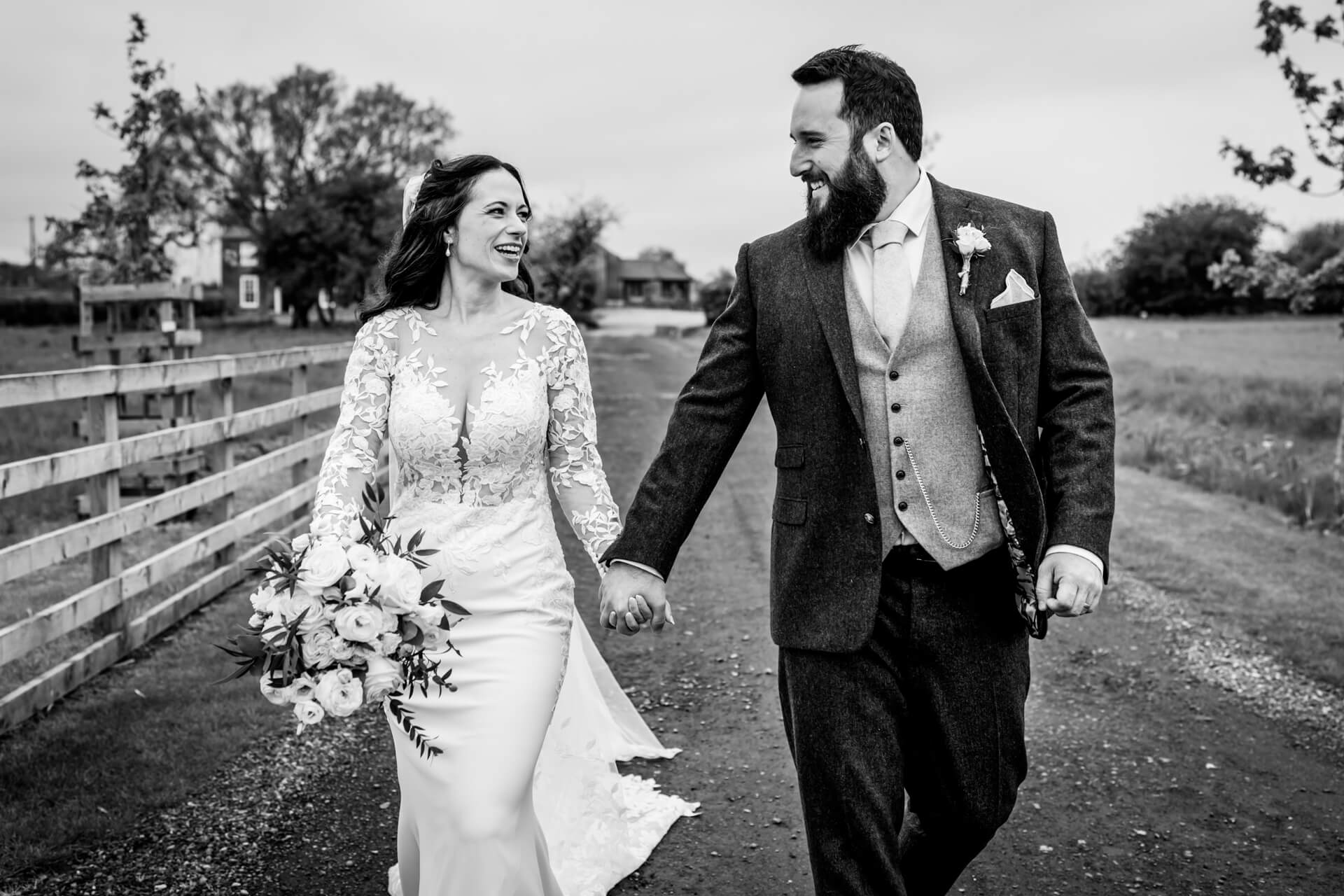 Newlyweds walking joyfully in countryside setting at Thirsk Lodge barns