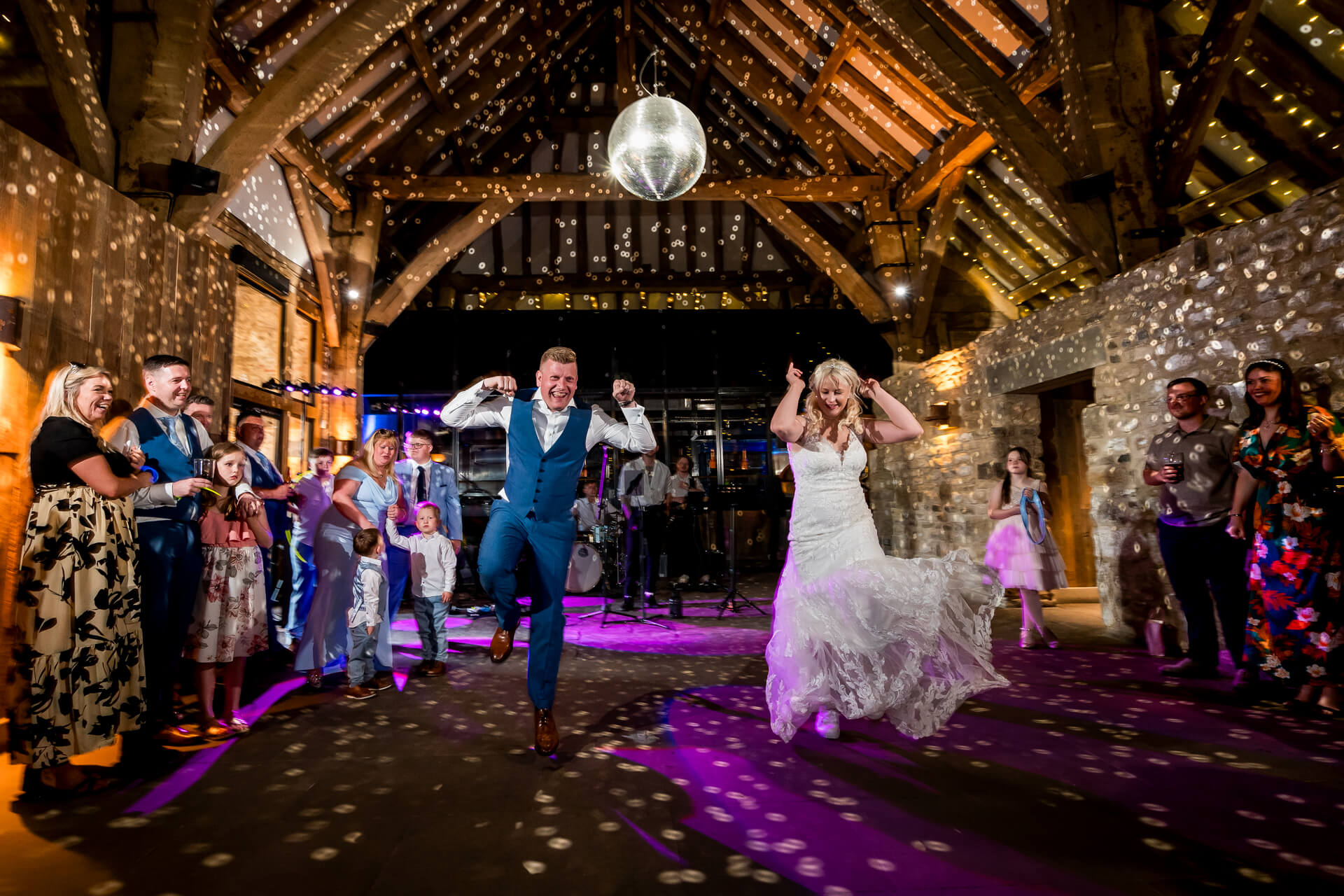 Bride and groom dancing joyfully at rustic wedding reception at Tithe Barn