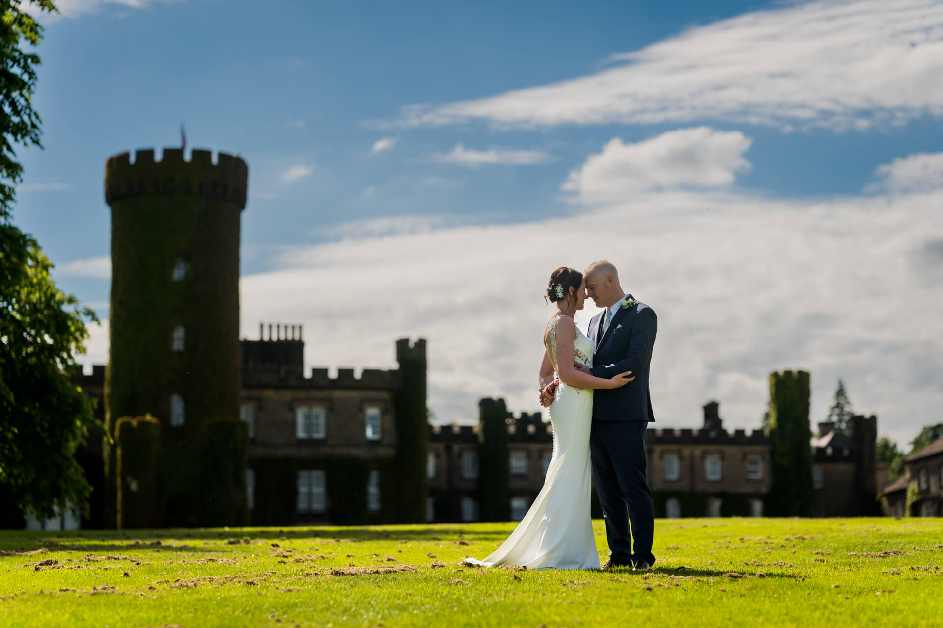 Bride and groom embracing near historic Swinton Park Castle