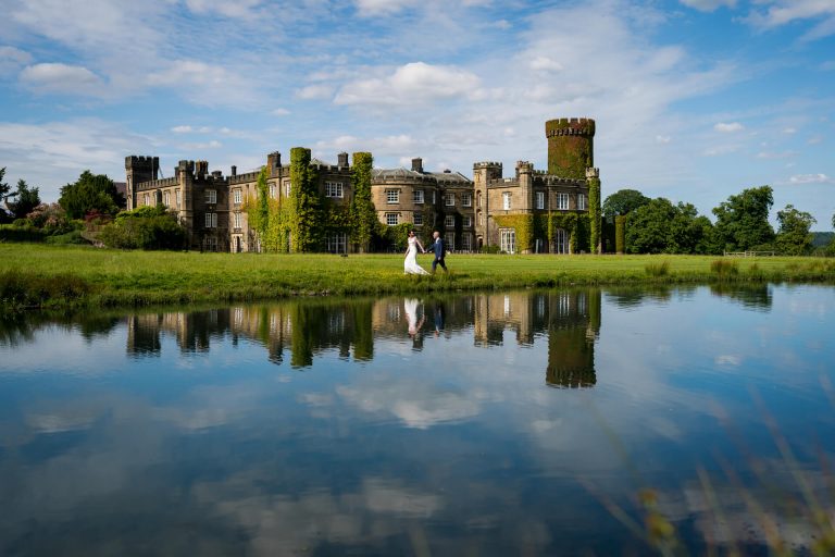Couple running by Swinton Park Castle with reflection in pond