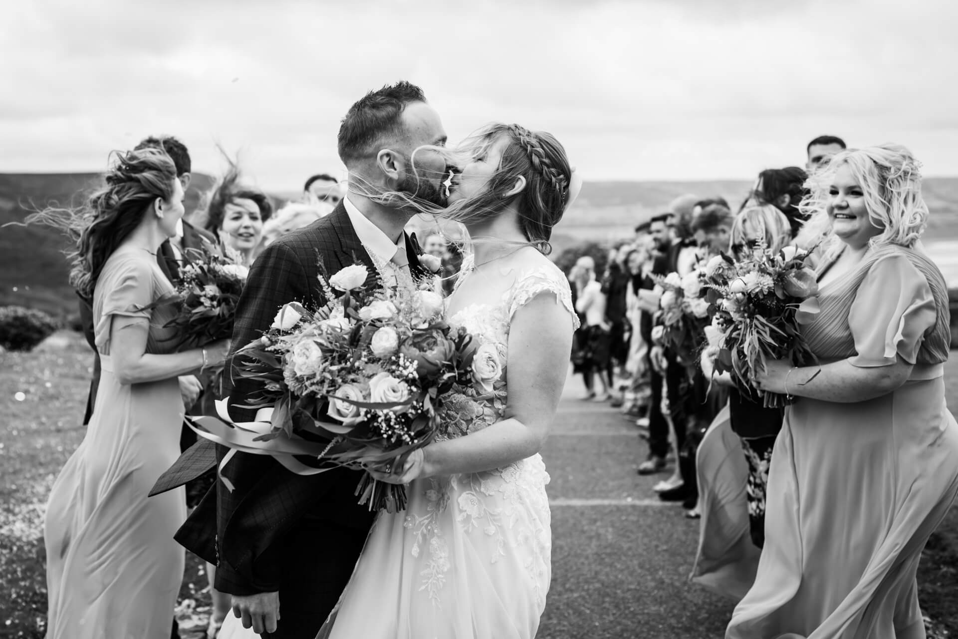 Bride and groom kissing at wedding with guests