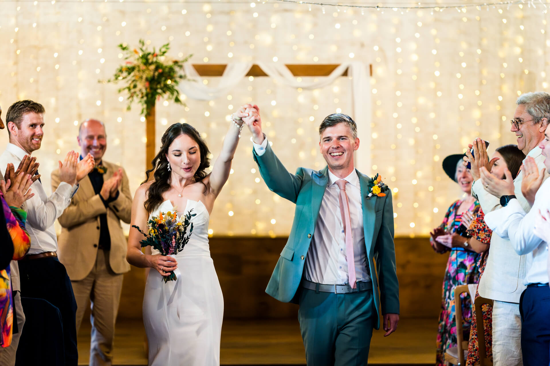 Newlyweds leaving ceremony amidst cheering guests at East Riddlesden Hall