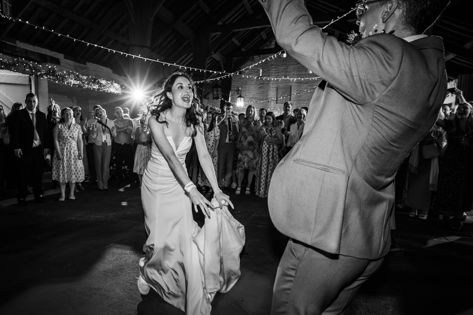 Bride and groom dancing joyously at wedding reception at East Riddlesden Hall