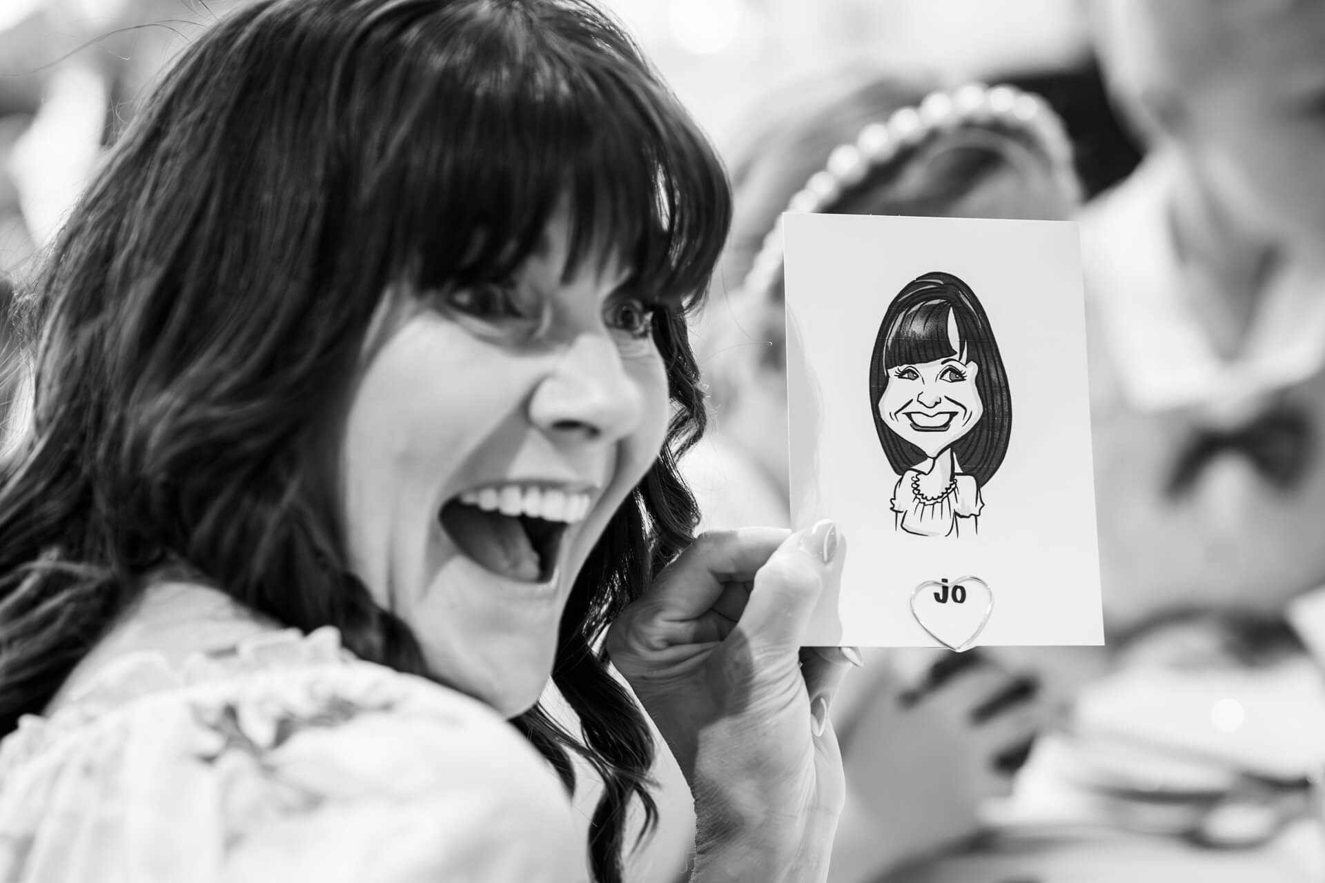 Woman laughing, holding caricature drawing of herself