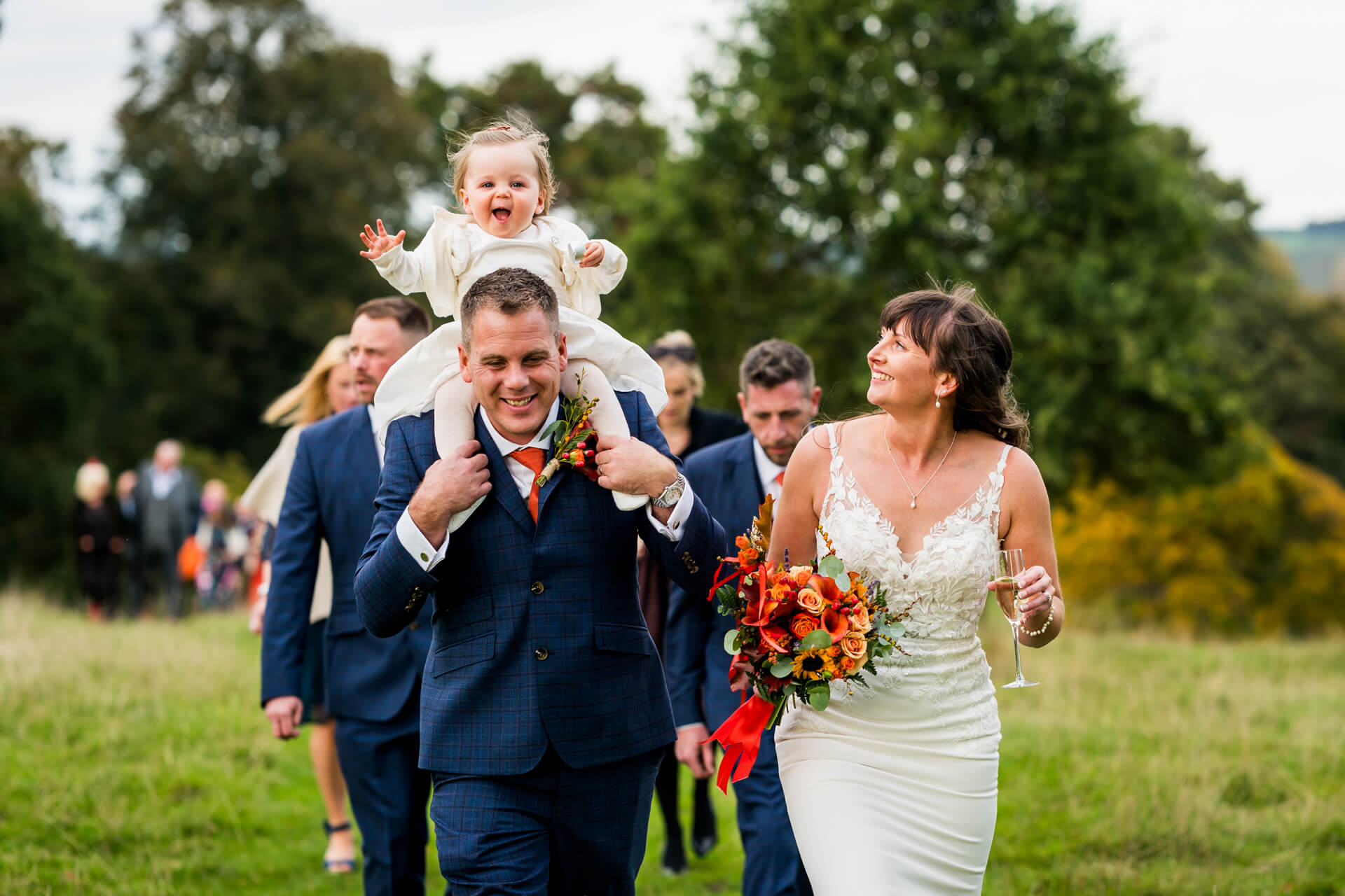 Joyful wedding scene with child riding groom's shoulders