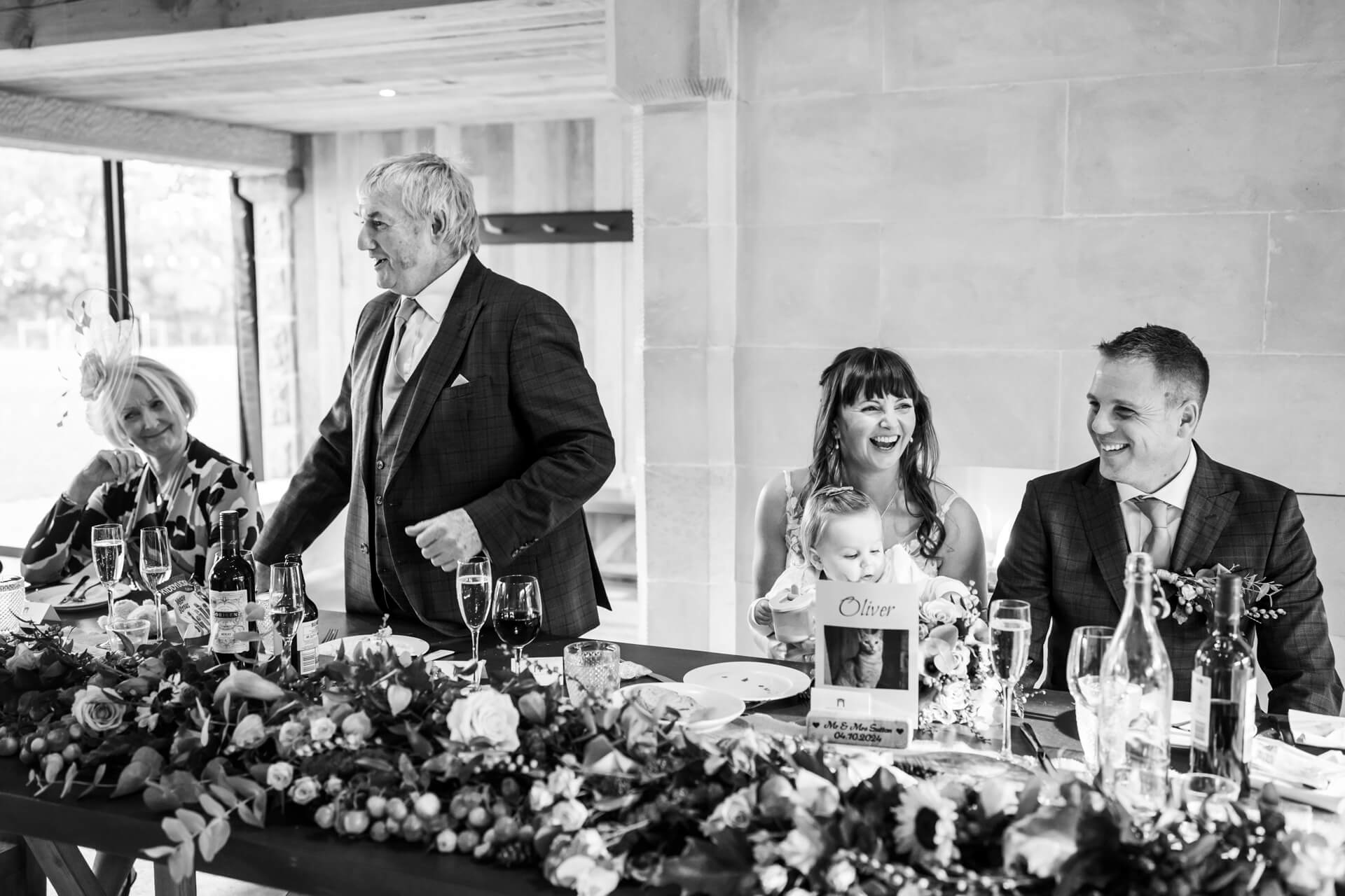 Family enjoying wedding reception at decorated table, black and white