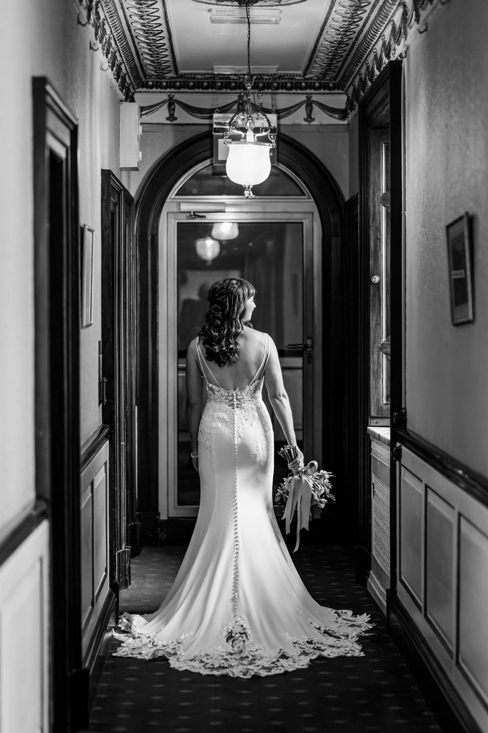 Bride walking down ornate corridor in elegant gown at Swinton Park