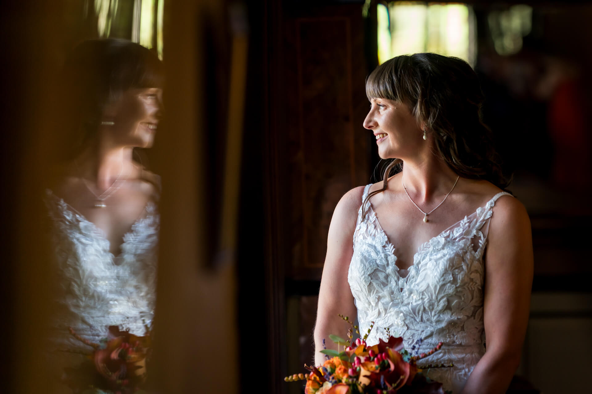 Bride smiling reflected in mirror holding bouquet