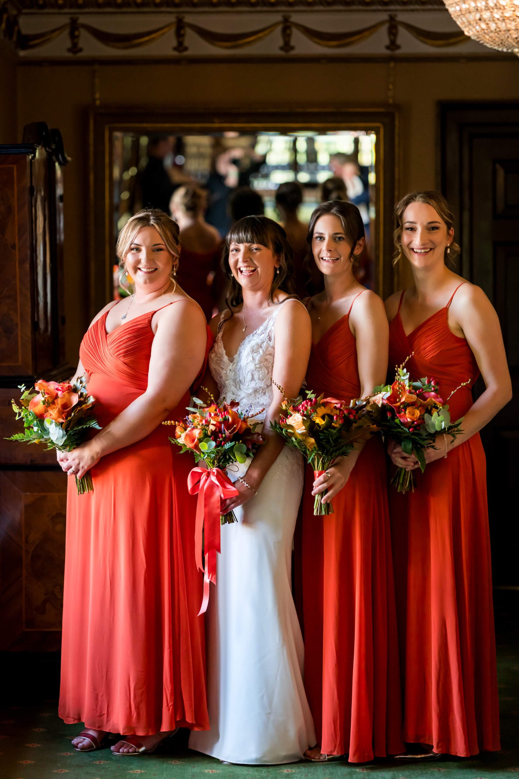 Bride and bridesmaids smiling in red dresses with bouquets