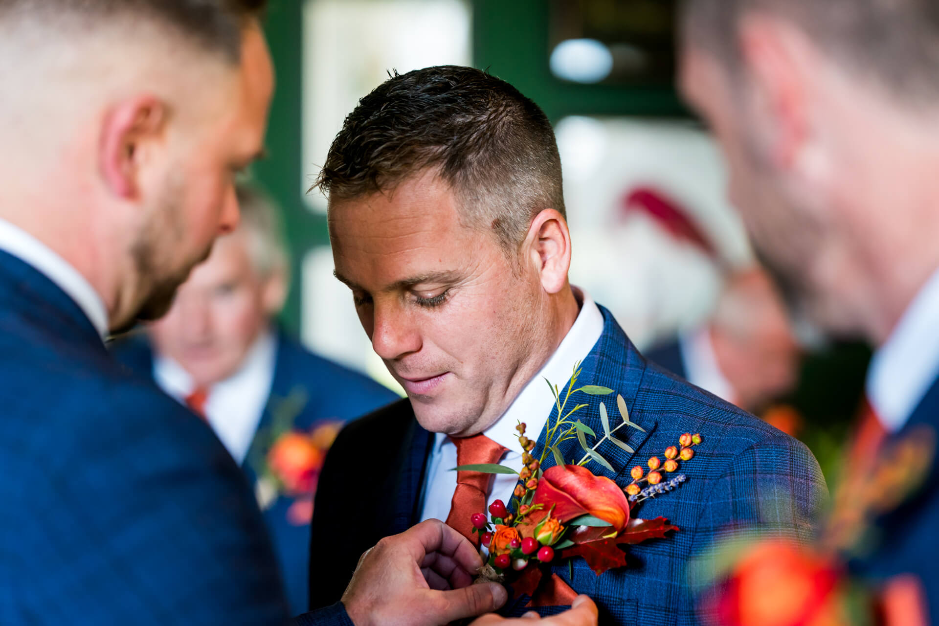 Groom adjusting boutonniere on wedding day