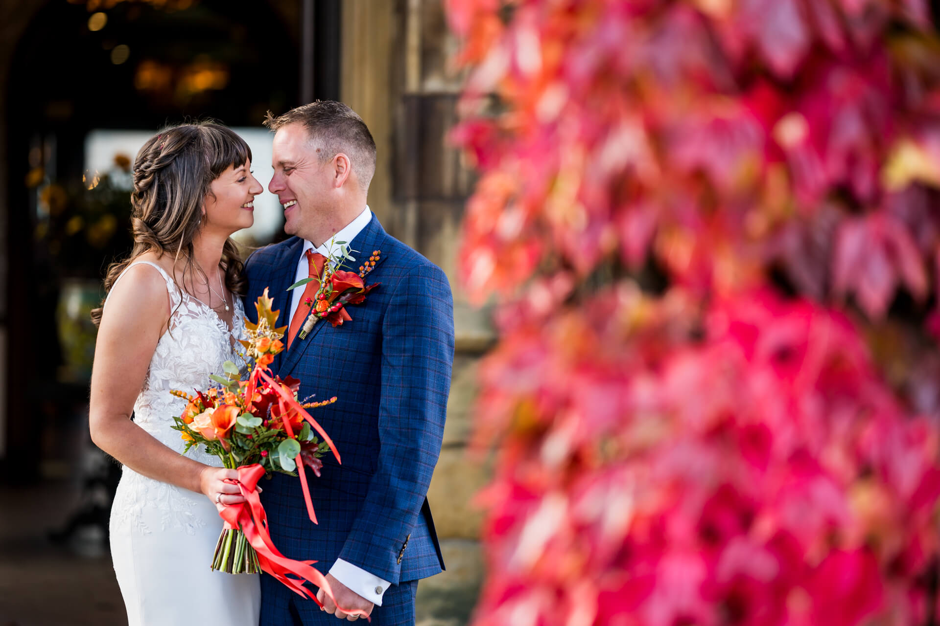 Bride and groom embracing among vibrant autumn leaves