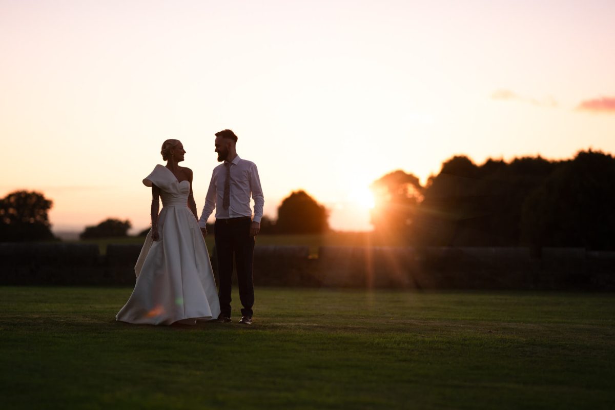 Couple in wedding attire at sunset in grassy field
