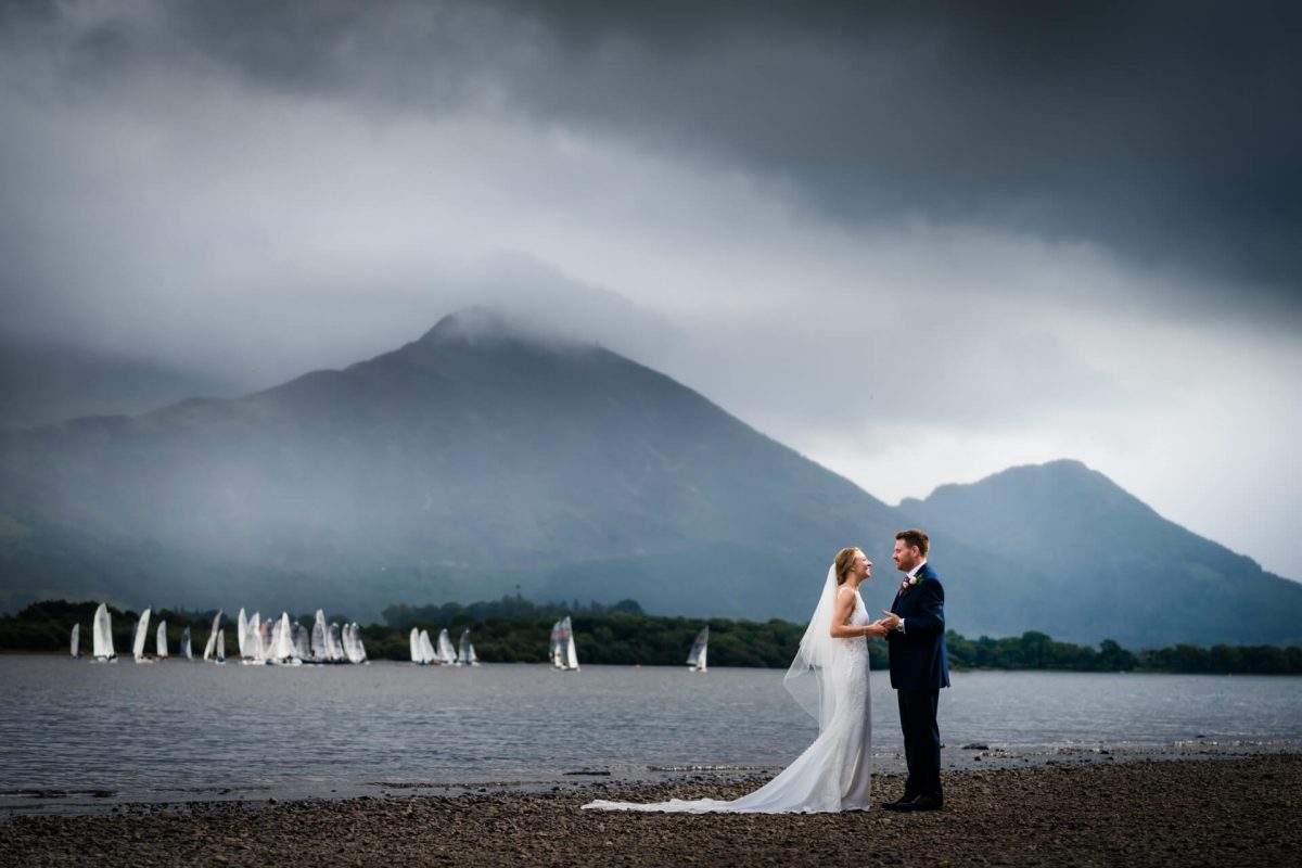 Wedding couple by lake with misty mountains