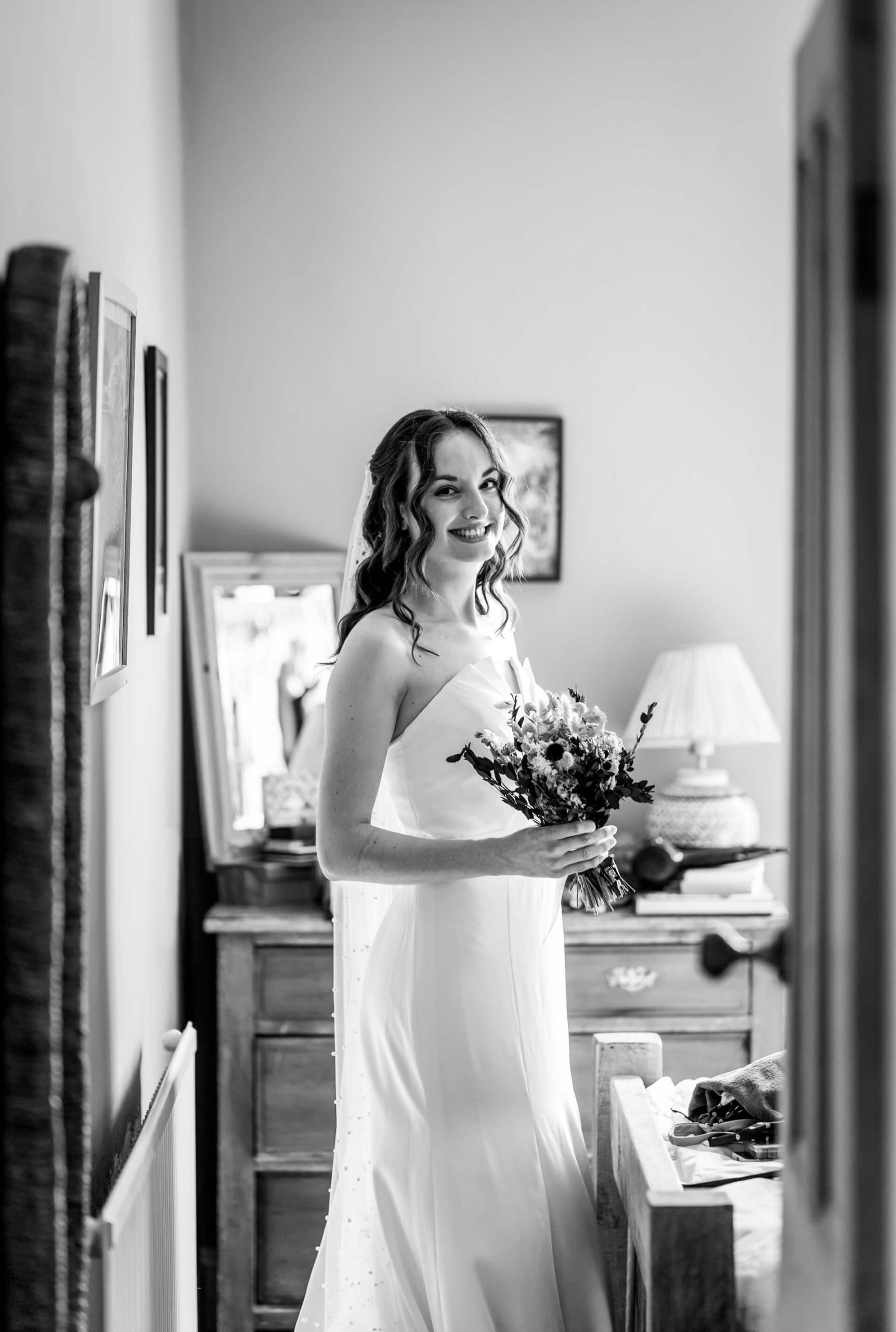 Bride smiling, holding bouquet in elegant room