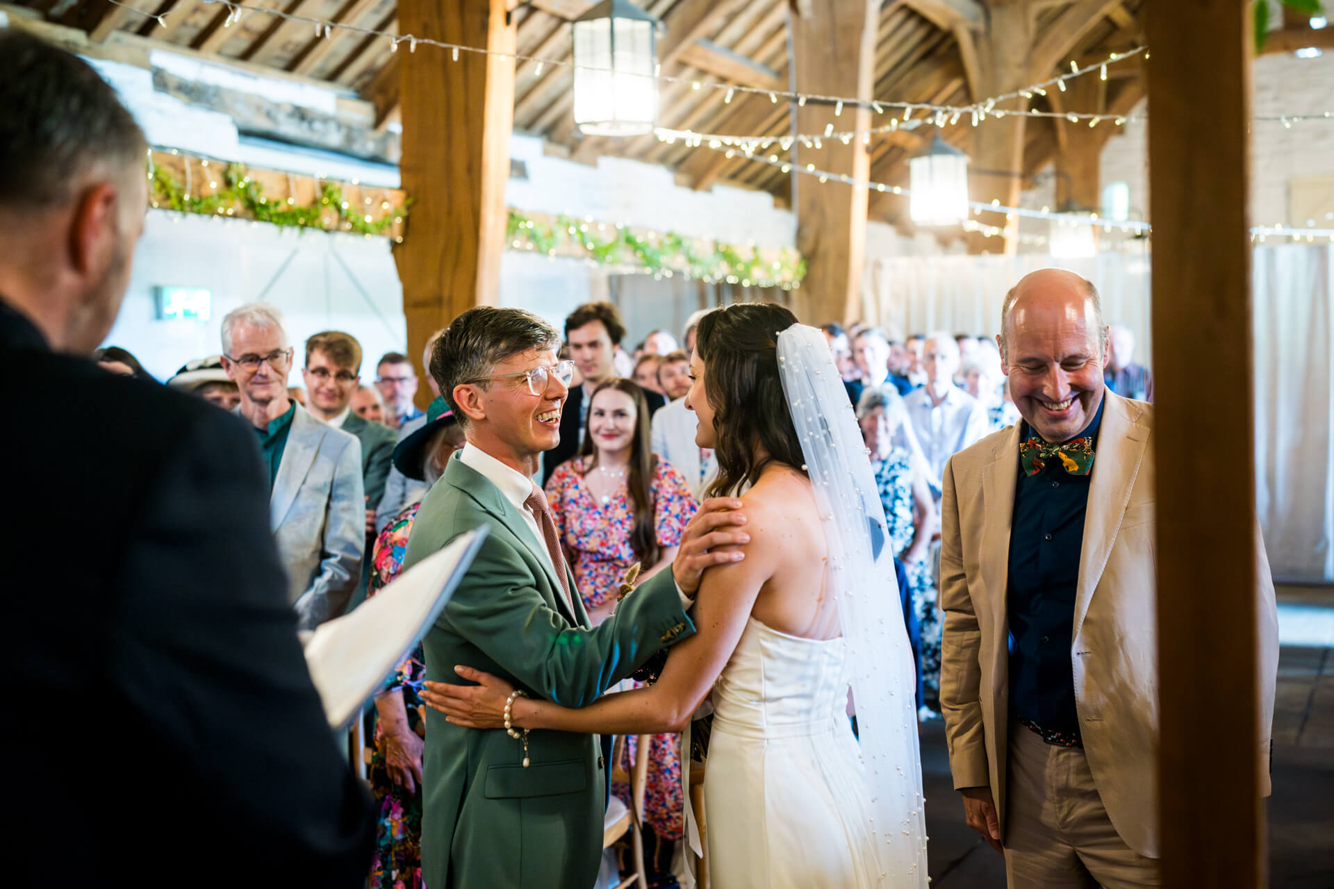Joyful wedding ceremony in a decorated barn setting at East Riddlesden Hall