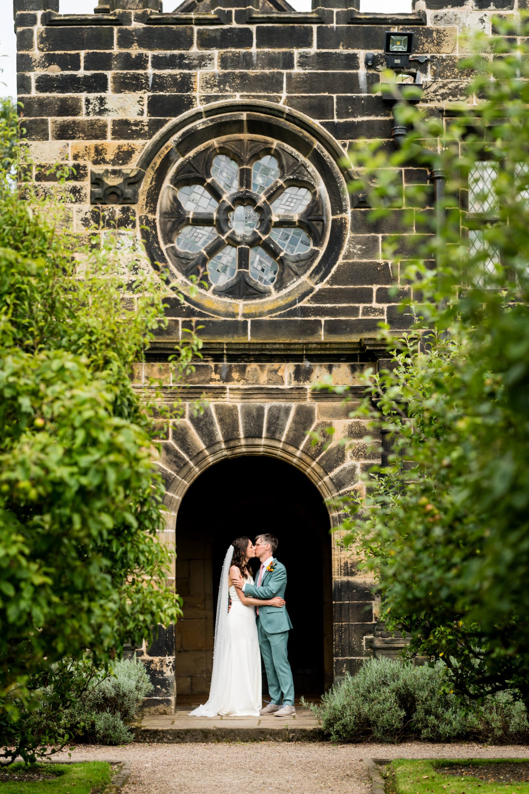 Couple kissing under historic archway at their wedding at East Riddlesden Hall