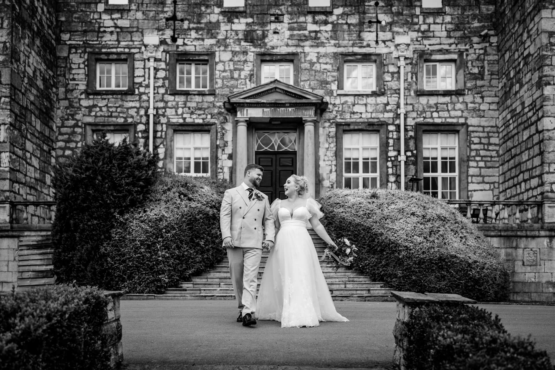 Bride and groom smiling outside historic stone building