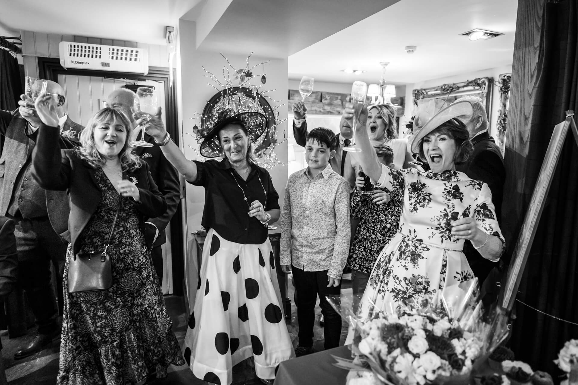 Joyful group toasting at wedding in black and white