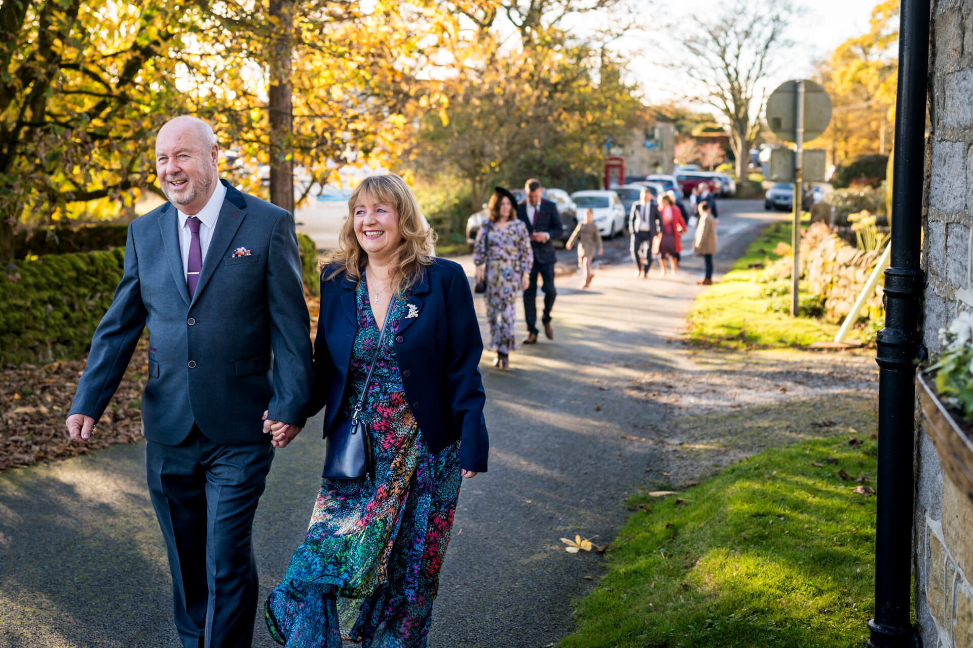 Wedding guests walking joyfully on sunny village street