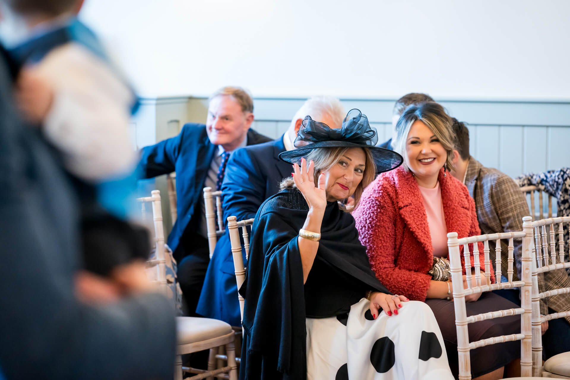Woman in black hat waving at wedding event