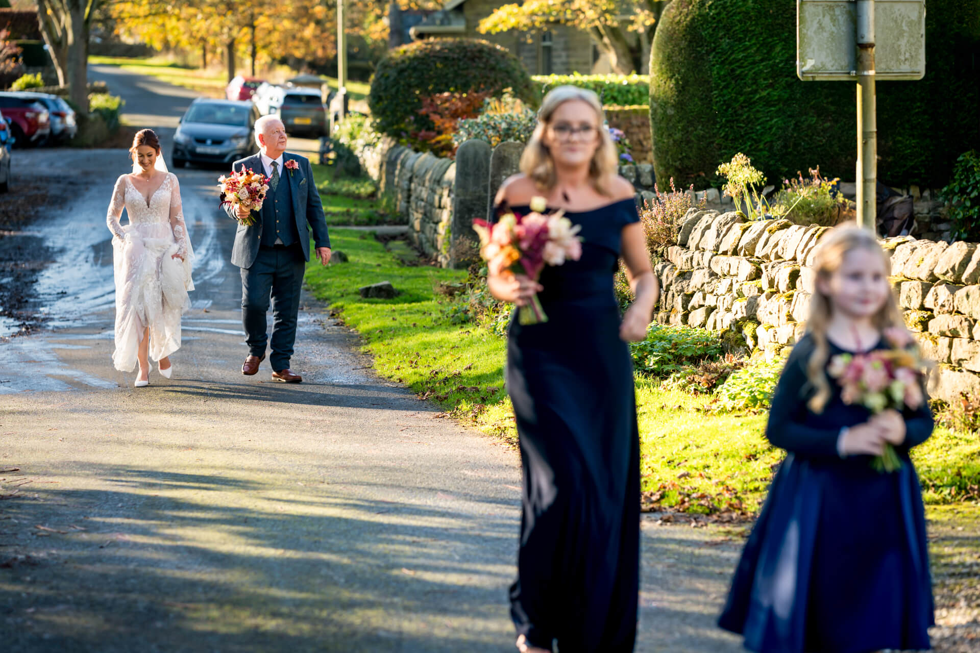 Wedding party walking along a sunlit village road
