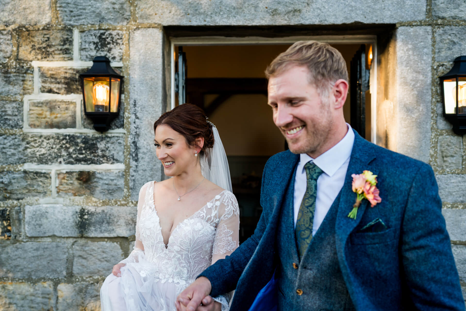 Bride and groom smiling outside stone building