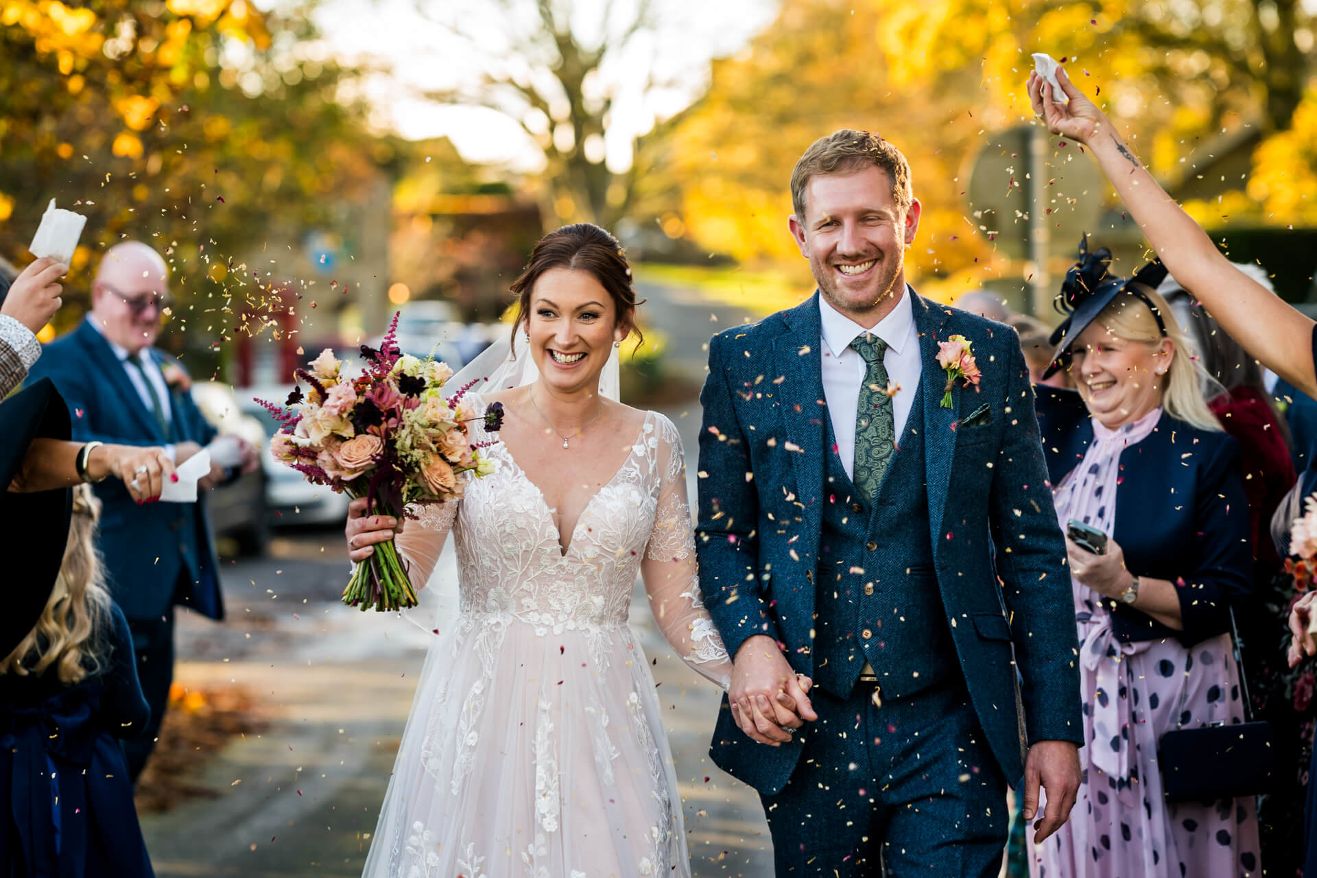 Newlyweds smiling, confetti thrown by guests at wedding
