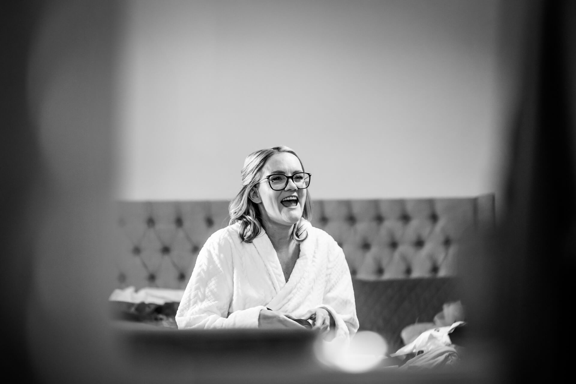 Joyful woman laughing in bathrobe with glasses