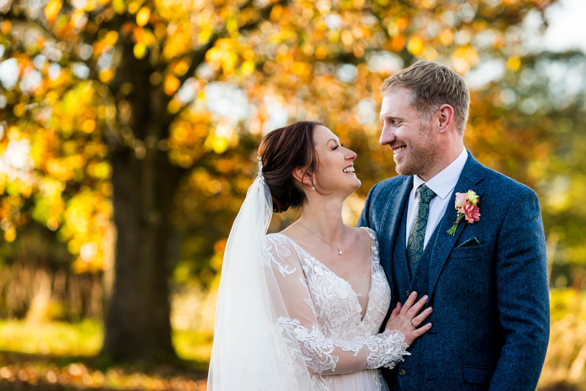 Bride and groom smiling in autumnal park