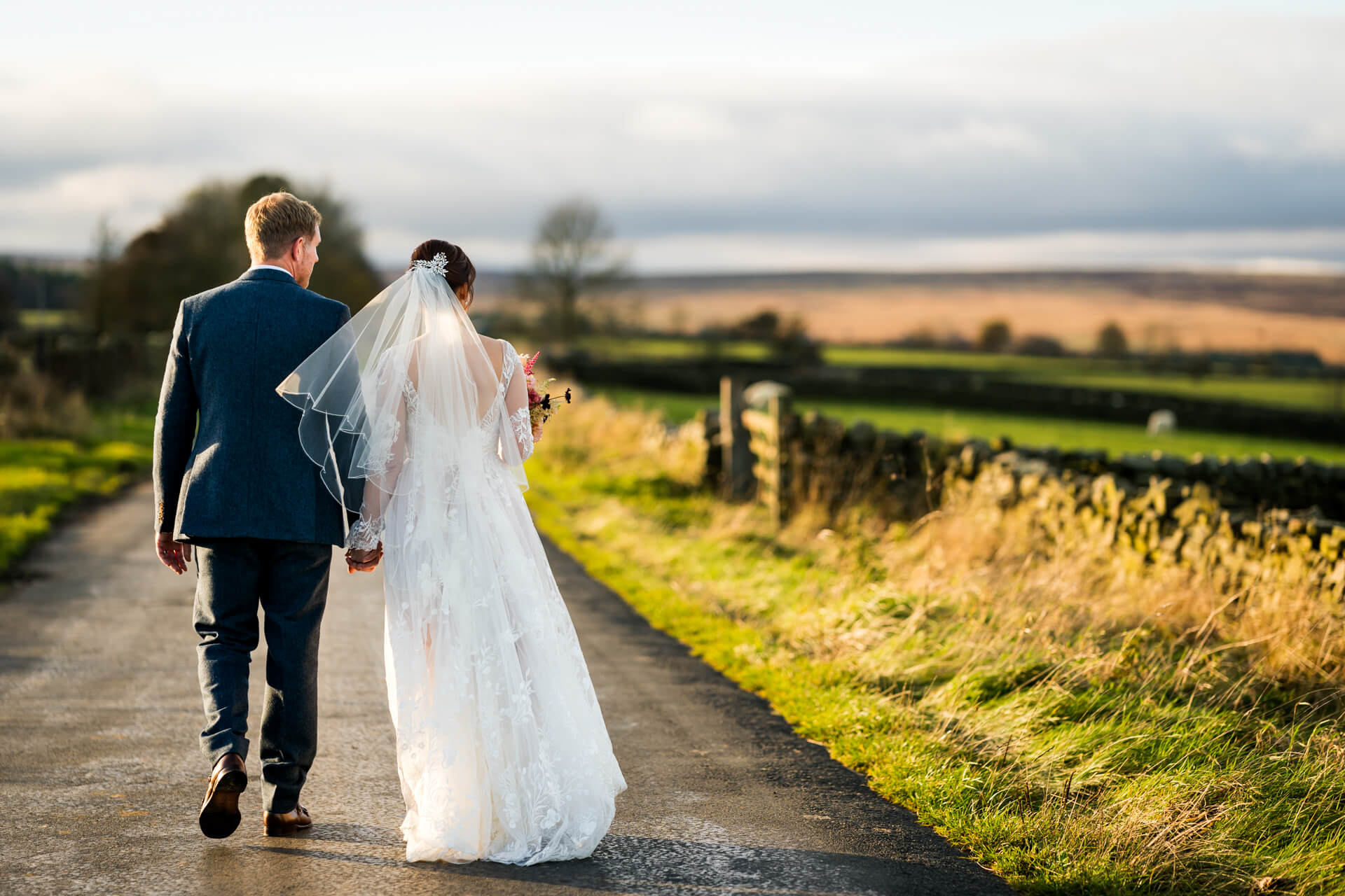 Bride and groom walking on country road at sunset