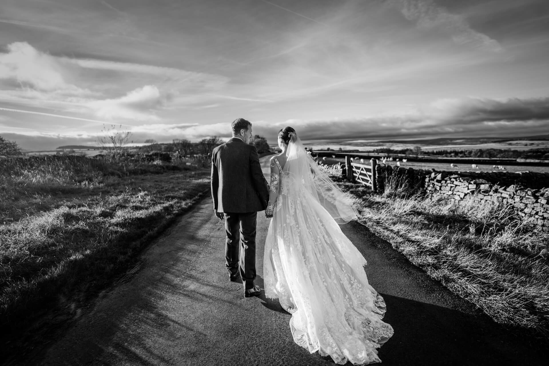 Bride and groom walking on country road near the Timble Inn, black and white.