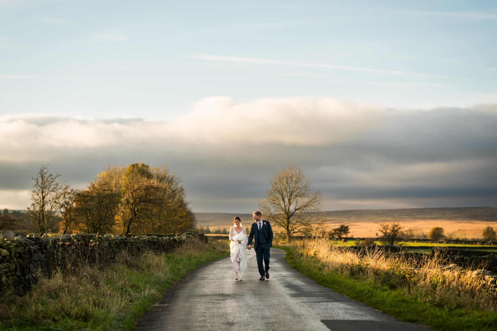 Newlyweds walking on country road at sunset