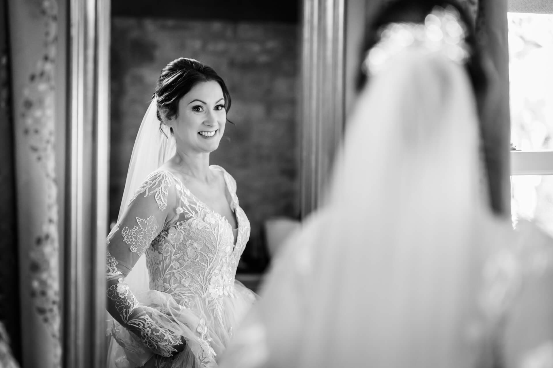 Bride smiling in mirror, elegant wedding dress